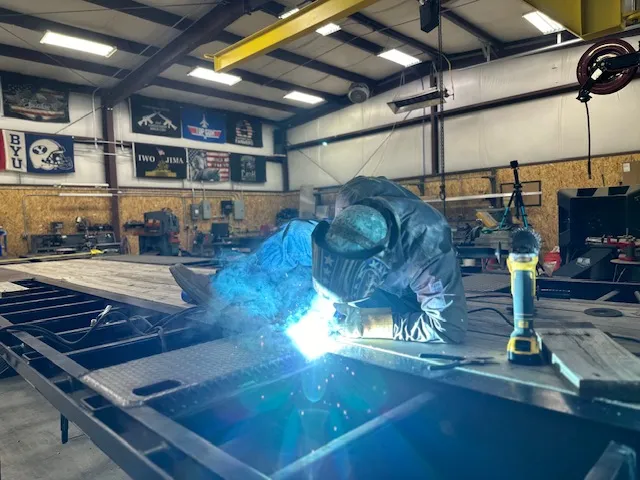 Welder working with sparks flying inside Freedom Fabrication shop