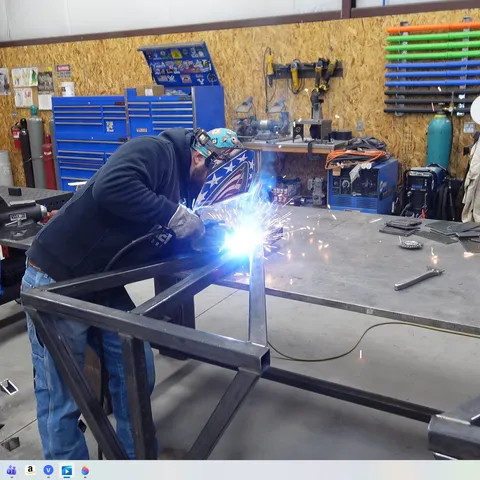 Welder working in shop with American flag backdrop