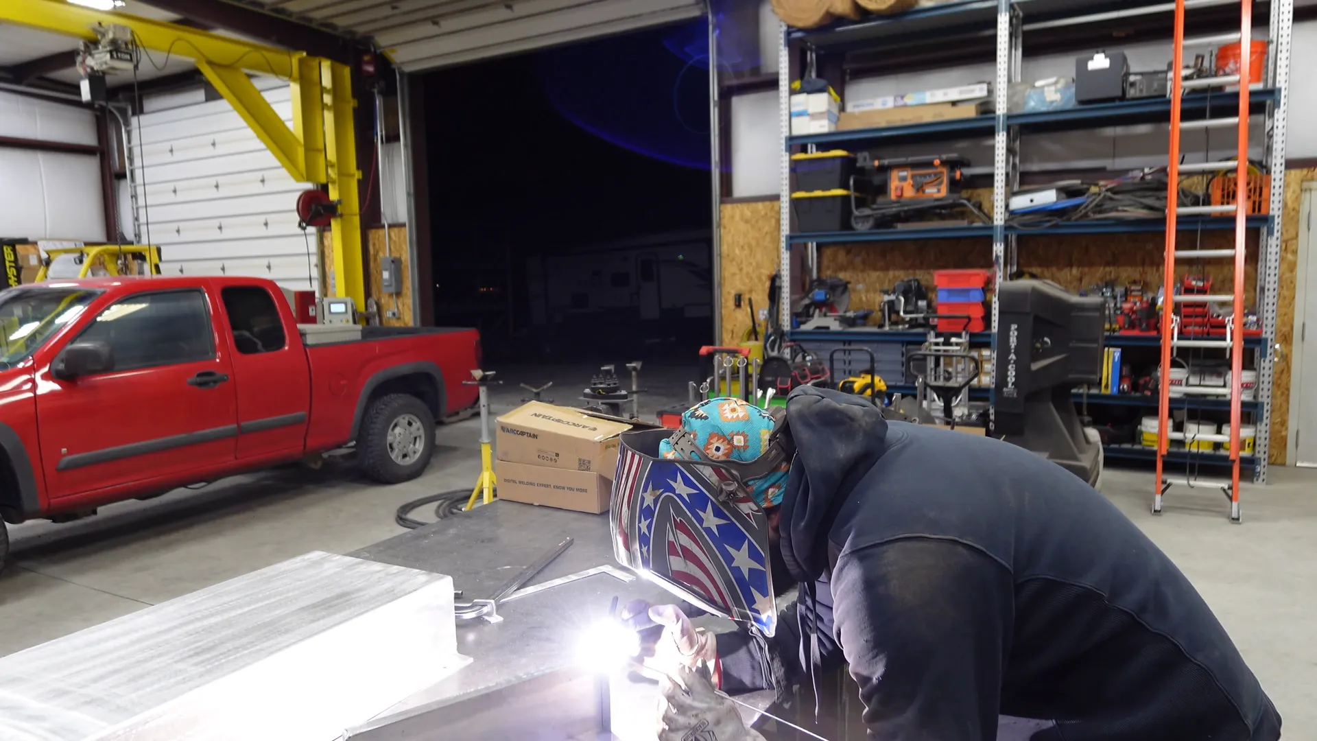 Welder working with sparks flying inside Freedom Fabrication shop